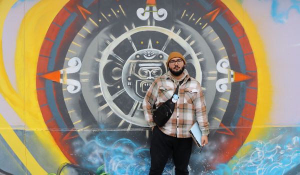 Oscar Sanchez stands in front of a mural